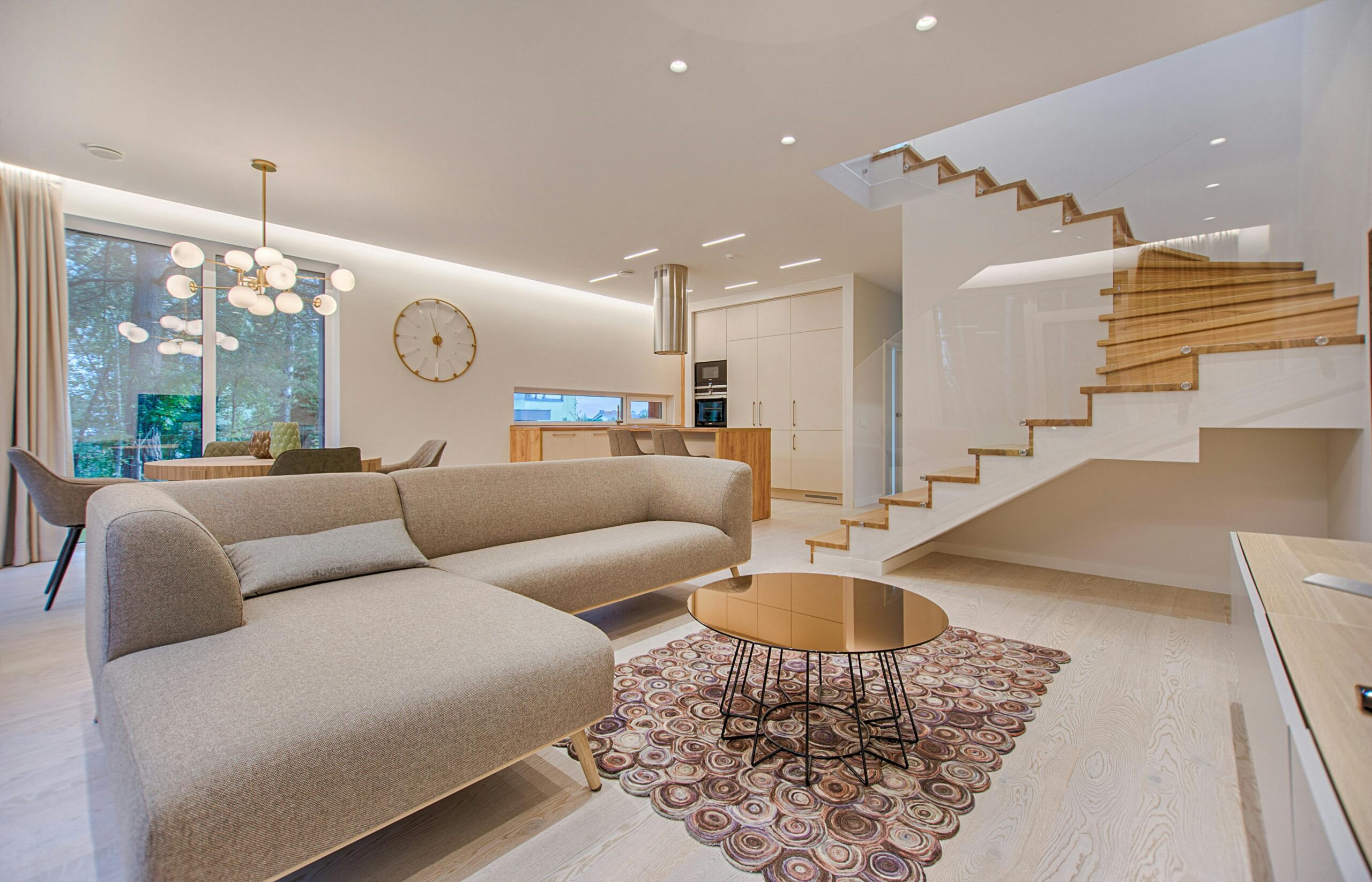 Sala de estar contemporânea com tons neutros, um sofá elegante e uma elegante escada de madeira.